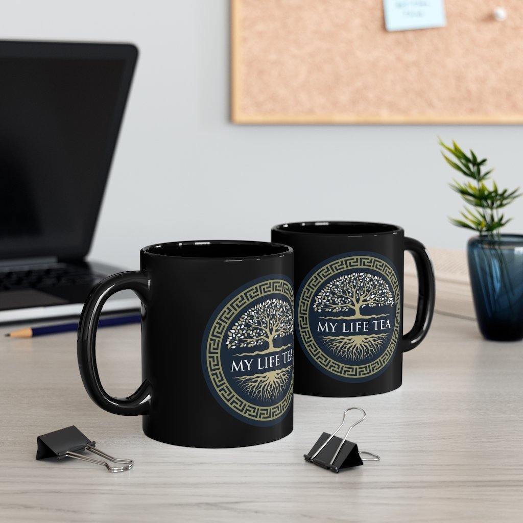 Two My Life Tea black mugs on a desk beside a plant